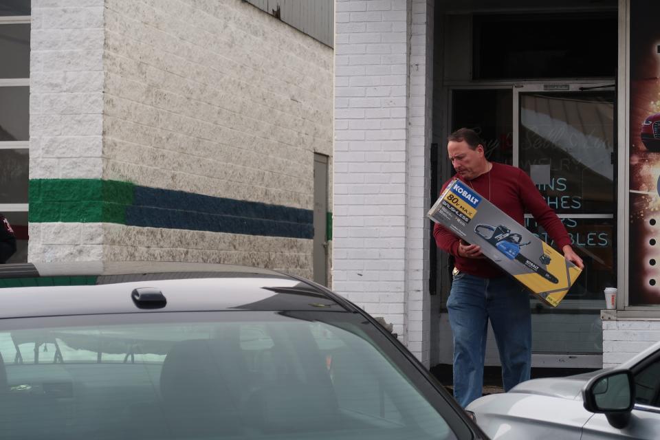 A law enforcement official carries a confiscated chainsaw out of Royal Crown Pawn in Greece Thursday.