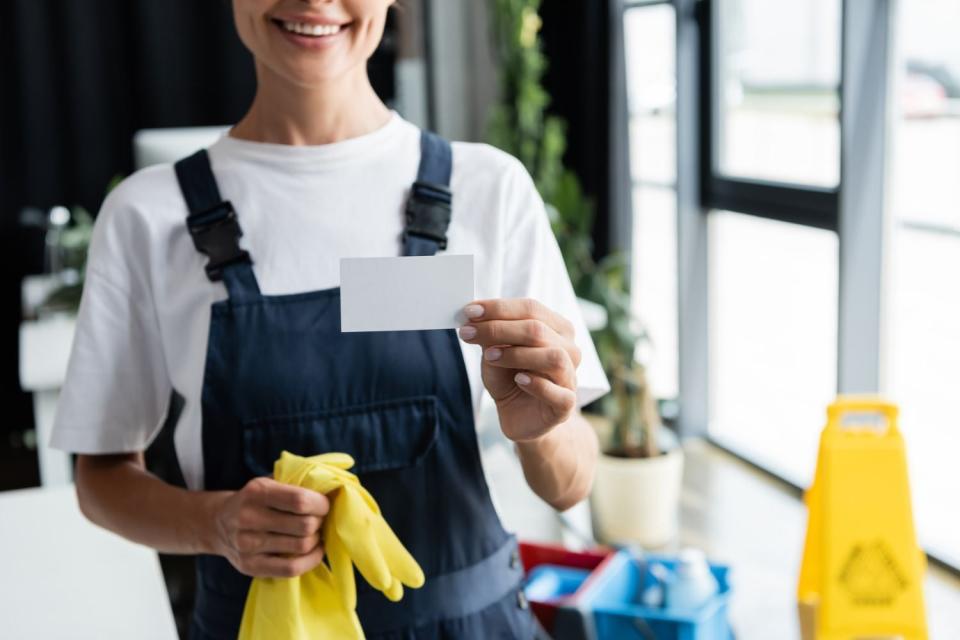 A person smiles reading a card, holding yellow gloves.