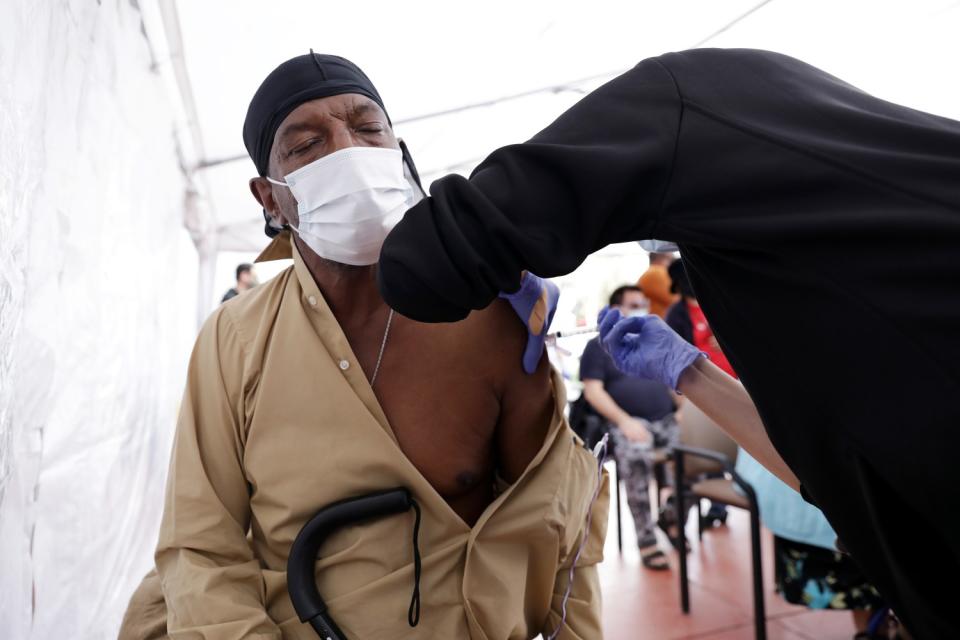 James Smith, 64, of Los Angeles, left, gets vaccinated by nurse practitioner Laura Fisher in South L.A.