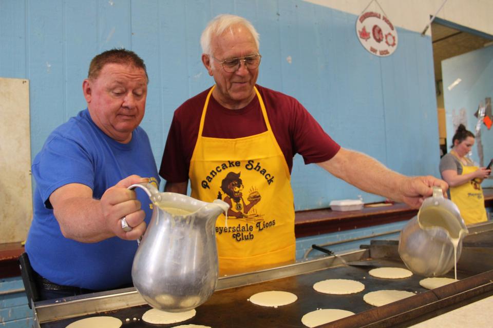 Clarence Baer and Mike Sipple pour pancake batter onto the griddle at the Lions Pancake Shack during the Pennsylvania Maple Festival in Meyersdale on Saturday. The Pancake Shack will reopen starting Wednesday through Sunday.