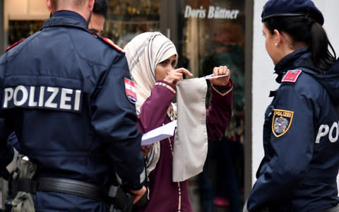 Police officers ask a woman to unveil her face in Zell am See, Austria - Credit: BARBARA GINDL/AFP/Getty Images