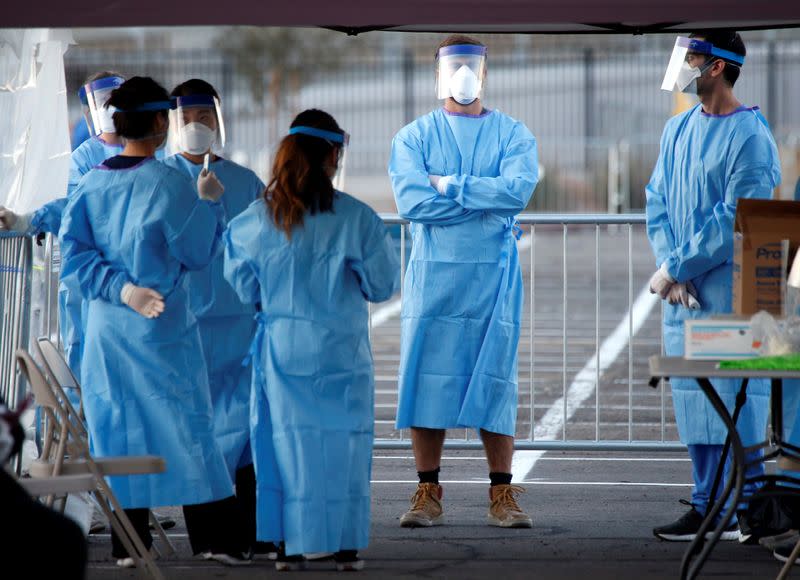 Medical students and physician assistants from Touro University Nevada wait to screen people in a temporary parking lot with spaces marked for social distancing in Las Vegas