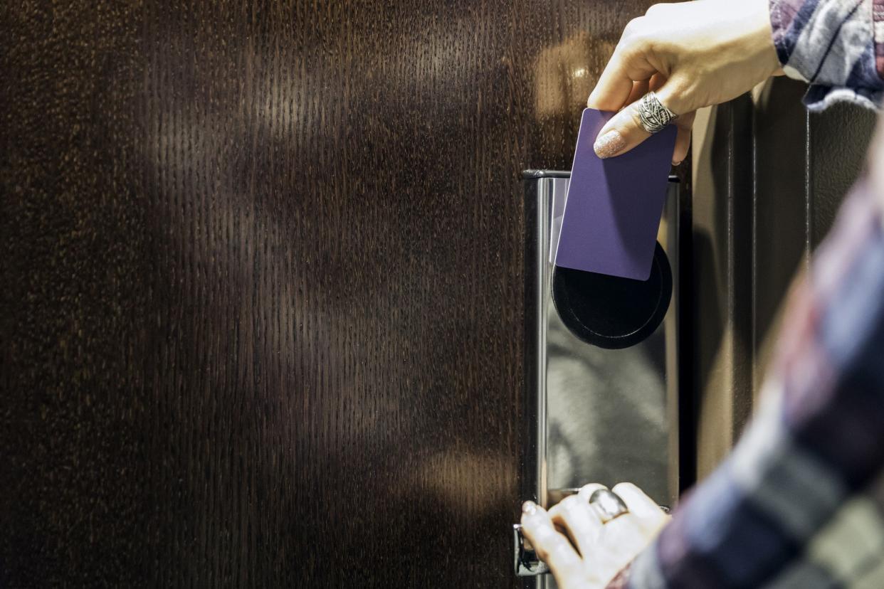 person using key to unlock hotel room