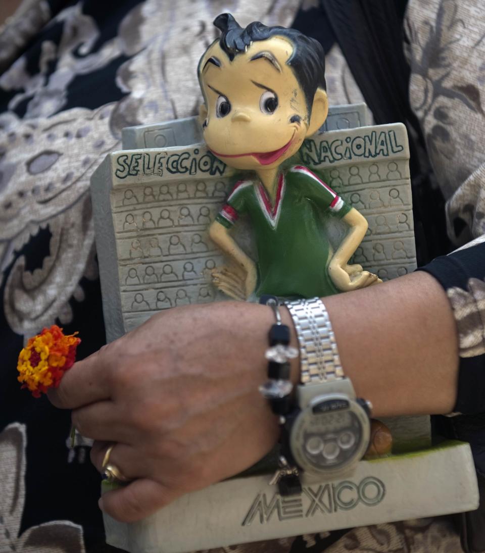 A woman holds an image depicting late Mexican comedian Mario Moreno 'Cantinflas' by his tomb at the Spanish Cementery in Mexico City, on August 12, 2011. Mexico Friday celebrates the 100th anniversary of Cantinflas' birth. AFP PHOTO/Yuri CORTEZ (Photo credit should read YURI CORTEZ/AFP/Getty Images)