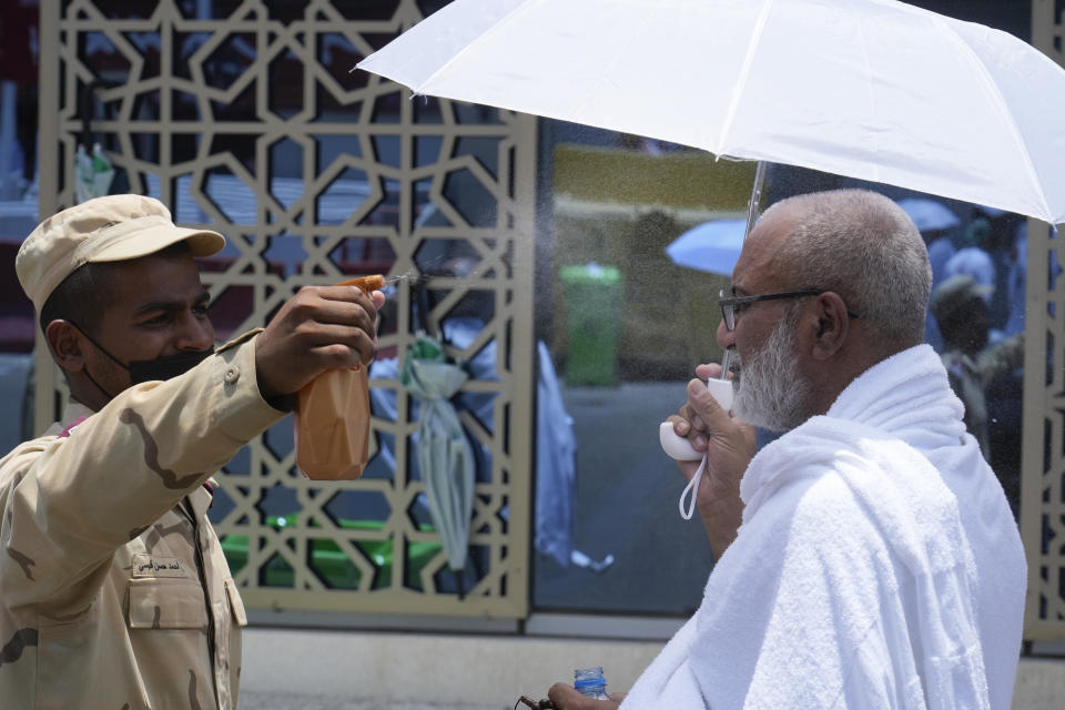 A police officer sprays cold water on a Muslim pilgrim at the Mina tent camp in Mecca, Saudi Arabia, during the annual Hajj pilgrimage, Monday, June 26, 2023. Muslim pilgrims are converging on Saudi Arabia's holy city of Mecca for the largest Hajj since the coronavirus pandemic severely curtailed access to one of Islam's five pillars. (AP Photo/Amr Nabil)