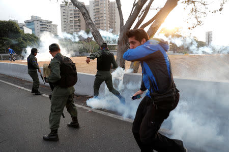 Military members react to tear gas, near the Generalisimo Francisco de Miranda Airbase "La Carlota", in Caracas, Venezuela April 30, 2019. REUTERS/Carlos Garcia Rawlins