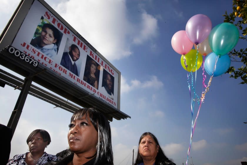 Activists Vicky Lindsey, center, Pam Carolina, left, and Teresa Haro pose with a billboard showing murder victims in urging a stop to violence in Compton. Lindsey has helped many victims' families since her son was killed 20 years ago