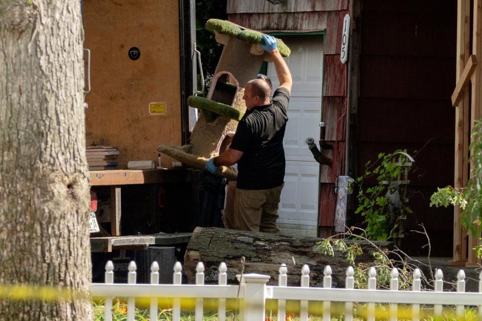 A crime laboratory officer moves a cat scratching post as law enforcement searches the home of Rex Heuermann (AP)