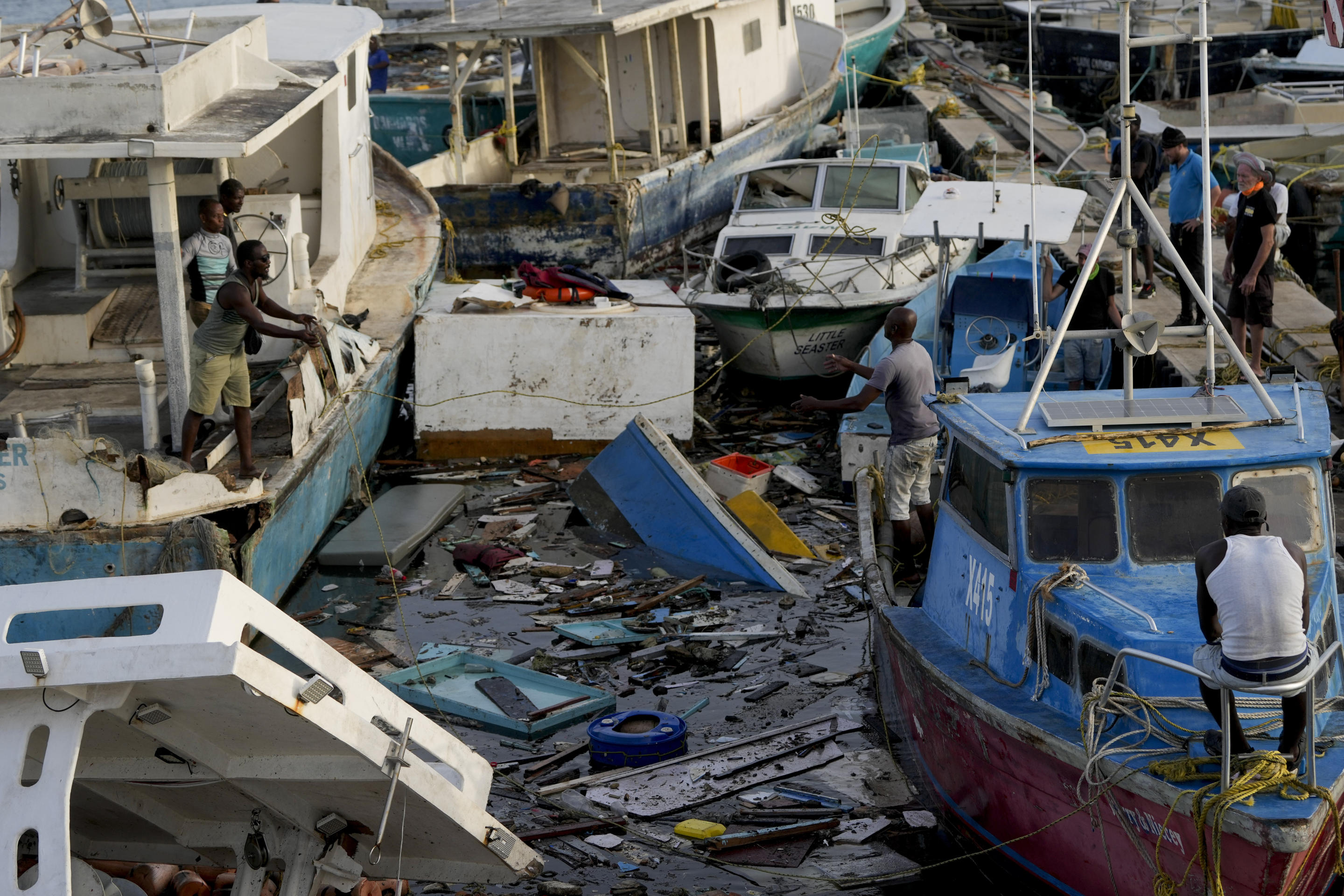 A fisherman throws a rope across boats damaged by Hurricane Beryl at Bridgetown Fisheries, Barbados.