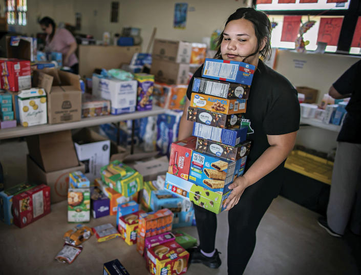 Gabriella Duran helps at the Mora Head Start building sort through food donated to families choosing to remain in Mora, N.M., on Wednesday, May 4, 2022. Weather conditions described as potentially historic are on tap for New Mexico on Saturday, May 7, and over the next several days as the largest fire burning in the U.S. chews through more tinder-dry mountainsides. (Jim Weber/Santa Fe New Mexican via AP)