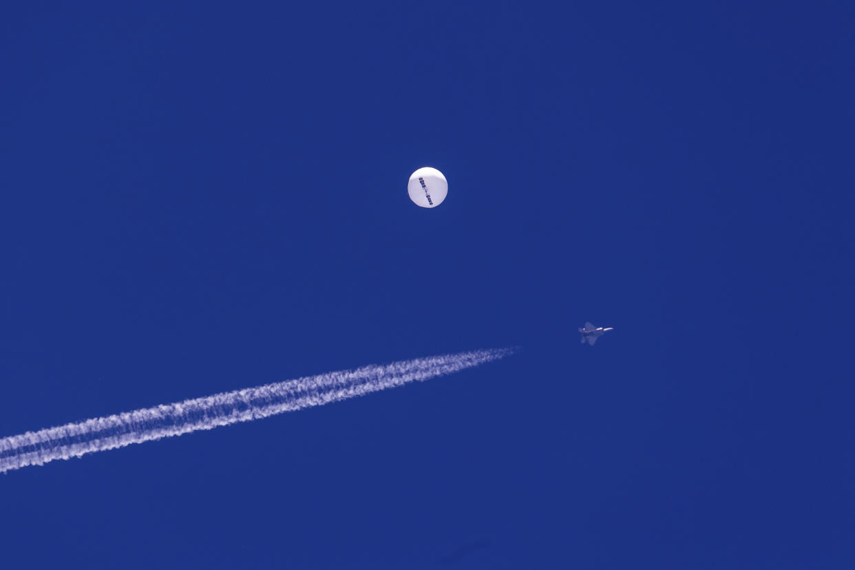 A jet flies by a suspected Chinese spy balloon as it floats off the coast near Myrtle Beach, S.C., in February 2023.  (Chad Fish via AP)