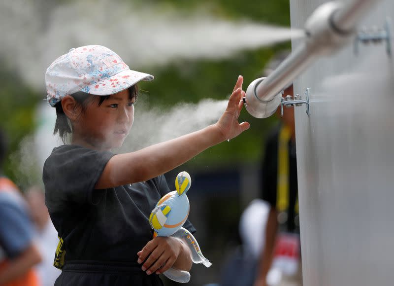 FILE PHOTO: A visitor experiences a large-scale misting tower dispensing ultra-fine mist during a proving test of heat countermeasures for the Tokyo 2020 Olympic and Paralympic Games in Tokyo