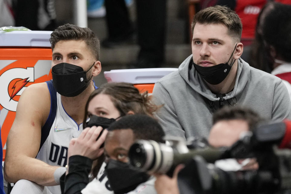 Dallas Mavericks guard Luka Doncic, right, watches from the bench during the second half of the team's NBA basketball game against the Houston Rockets, Friday, Jan. 7, 2022, in Houston. (AP Photo/Eric Christian Smith)