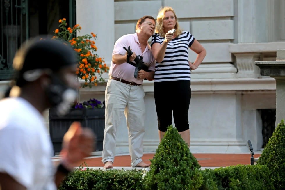 Armed homeowners Mark and Patricia McCloskey stand in front their house confronting protesters marching to St. Louis Mayor Lyda Krewson’s house in the Central West End of St. Louis, June 28, 2020. (Laurie Skrivan/St. Louis Post-Dispatch via AP, File)