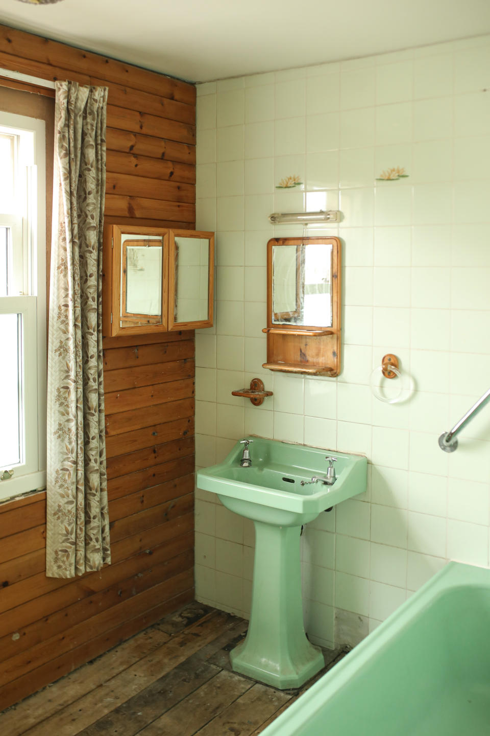 A dated bathroom with avocado sink and patterned curtains