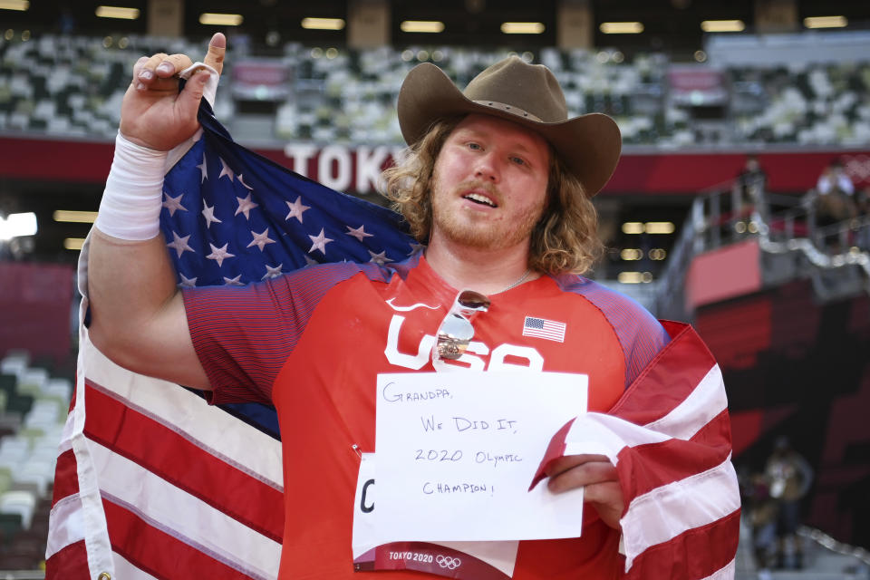 Ryan Crouser, of United States, holds a sign while celebrating winning the gold medal in the final of the men's shot put at the 2020 Summer Olympics, Thursday, Aug. 5, 2021, in Tokyo, Japan. (Matthias Hangst/Pool Photo via AP)