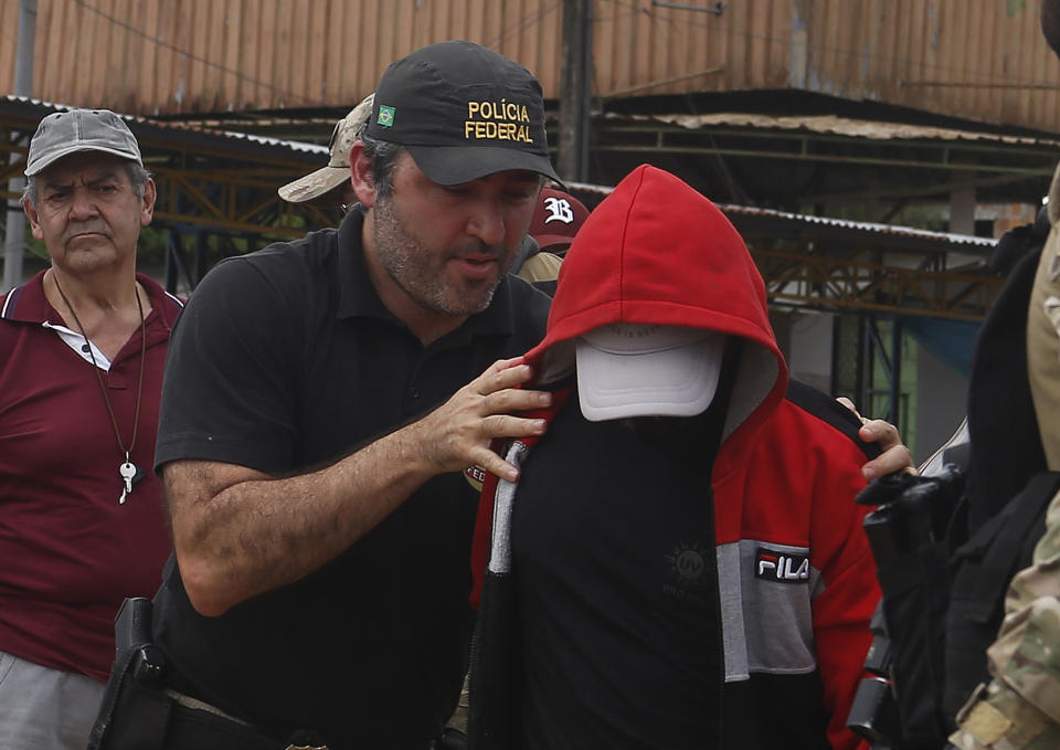 A federal police officer escorts a suspect towards a river in the area where Indigenous expert Bruno Pereira and freelance British journalist Dom Phillips disappeared, in Atalaia do Norte, Amazonas state, Brazil, Wednesday, June 15, 2022. Federal police said in a statement Tuesday night that they had arrested a second suspect in connection with the disappearance of Phillips and Pereira in a remote area of the Amazon. (AP Photo/Edmar Barros)