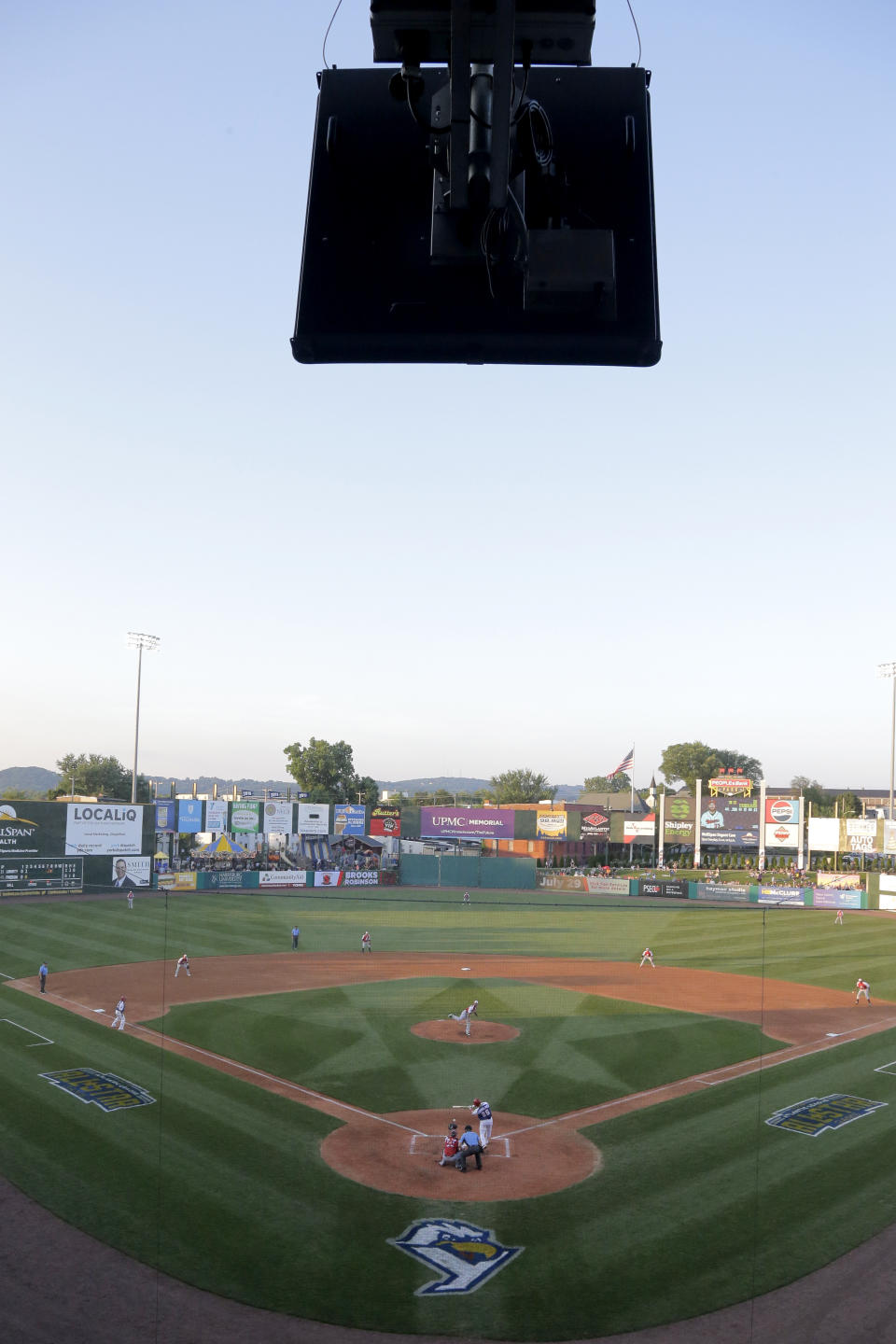 A radar device, top, is seen during second inning action in the Atlantic League All-Star minor league baseball game, Wednesday, July 10, 2019, in York, Pa. Home plate umpire Brian deBrauwere wore an earpiece connected to an iPhone in his ball bag which relayed ball and strike calls upon receiving it from a TrackMan computer system that uses Doppler radar. The independent Atlantic League became the first American professional baseball league to let the computer call balls and strikes during the all star game. (AP Photo/Julio Cortez)