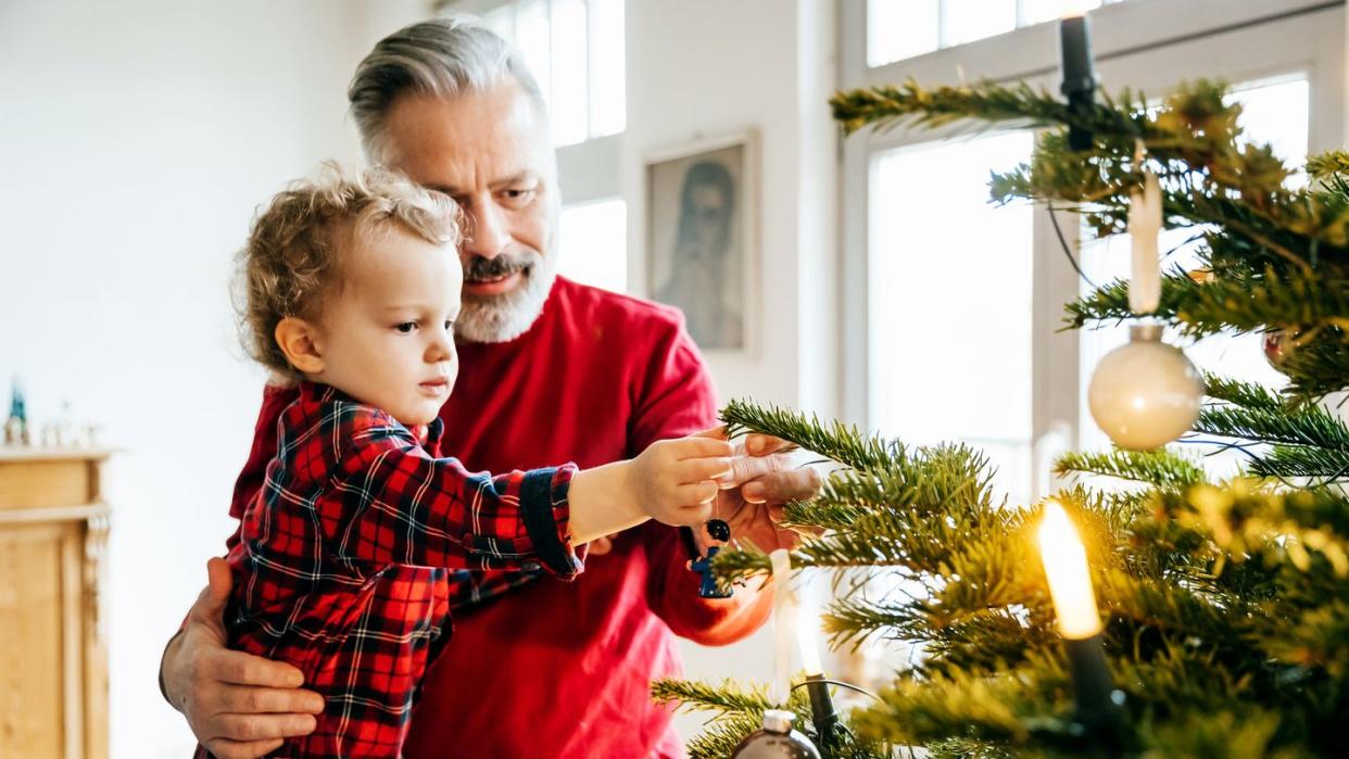 grandpa bonding with grandson while decorating christmas tree