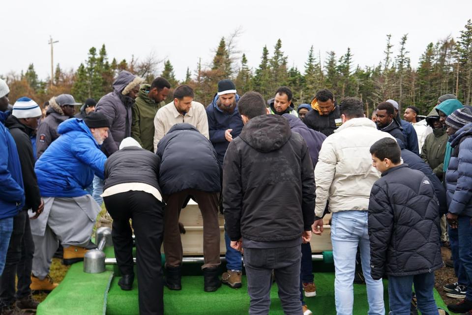 Men attending the funeral of Omar Mohammed offer a prayer as they lower his casket into the ground at the Muslim Association of Newfoundland and Labrador cemetary on Bauline Line Sunday morning. 