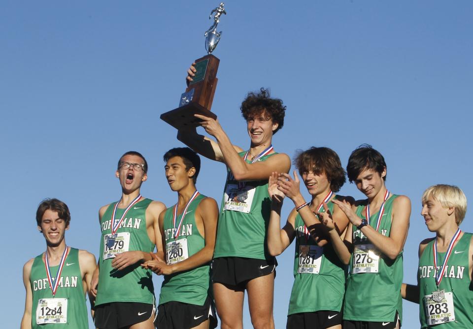 Dublin Coffman's Liam Shaughnessy holds up the Division I state runner-up trophy as his teammates celebrate their finish Nov. 6 at Fortress Obetz.