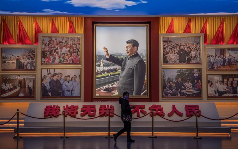 A visitors walks in front of pictures showing Chinese President Xi Jinping, at the Museum of the Communist Party of China, in Beijing - ROMAN PILIPEY/Shutterstock