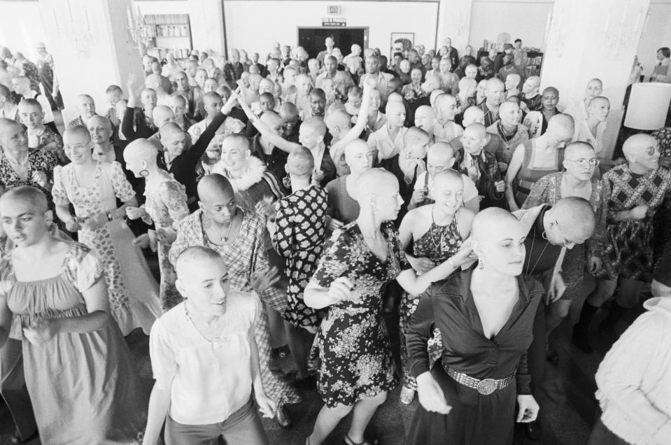 (Original Caption) 2/27/1975-Oakland, CA- More than 500 women from Synanon communities throughout California went prematurely bald, shaving their heads in a demonstration of women's liberation. The shaved heads symbolize Synanon women's acceptance of an equal responsibility--with Synanon men--for the management and operation of the foundation which re-educates drug addicts, juvenile delinquints and other character-disordered people. Here, some 200 Synanon women dance during a press conference.