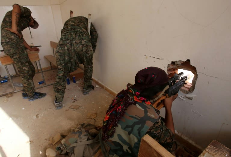 Fighters from the Kurdish People's Protection Units (YPG) take position in a classroom in the village of Maaruf near Hasakeh on July 16, 2015