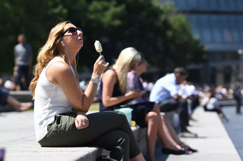 a woman sitting on a wall eating an ice cream