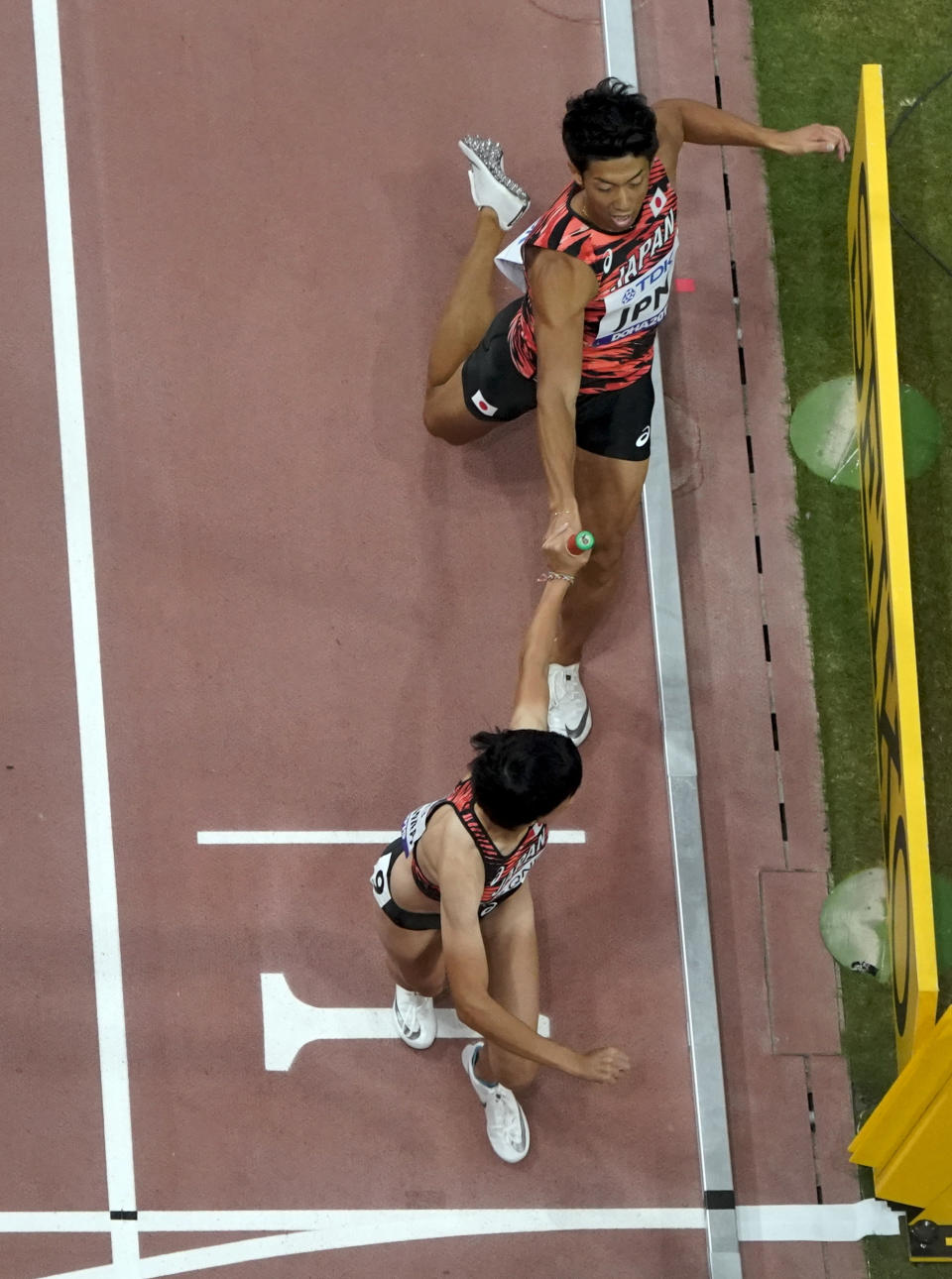 Japan's Tomoya Tamura hands the baton to Saki Takashima in a mixed 4 x 400 meter relay heat at the World Athletics Championships in Doha, Qatar, Saturday, Sept. 28, 2019. (AP Photo/Morry Gash)