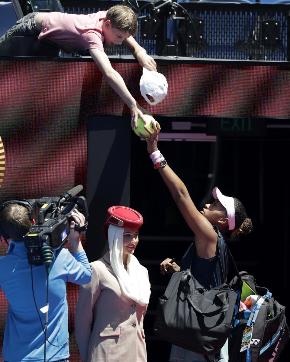 Japan's Naomi Osaka signs autographs for a fan as she leaves Rod Laver Arena following her quarterfinal win over Ukraine's Elina Svitolina at the Australian Open tennis championships in Melbourne, Australia, Wednesday, Jan. 23, 2019. (AP Photo/Kin Cheung)