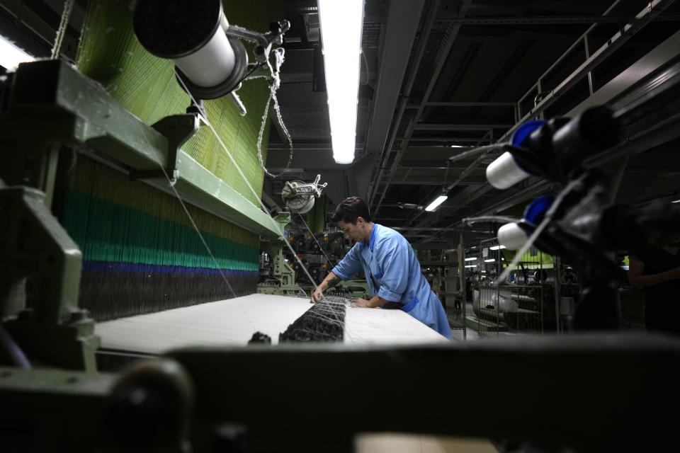 A woman works in a textile industry in Guanzate, northern Italy, Friday, Sept. 16, 2022. The energy crisis facing Italian industry and households is a top voter concern going into Sunday's parliamentary elections as fears grow that astronomically high bills will shutter some businesses and force household rationing by winter. Never in an Italian election campaign has energy been such a central talking point. (AP Photo/Antonio Calanni)