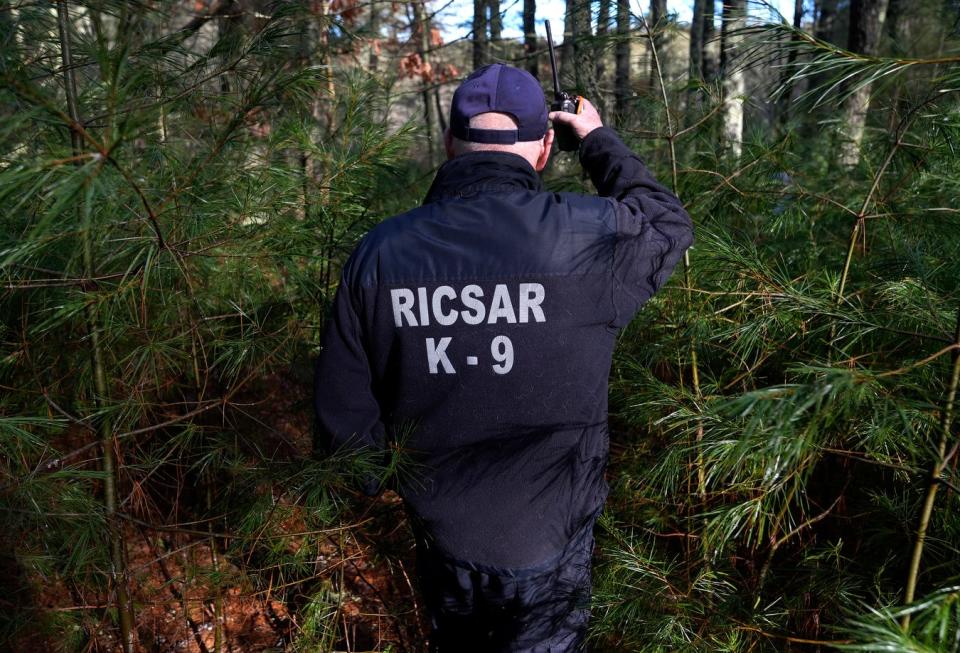 Mike Koster of Rhode Island Canine Search and Rescue follows dog Baylee through the woods on the former Ladd Center campus in Exeter while overseeing a training exercise.