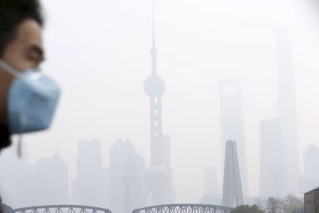 A man wearing a face mask walks on a bridge in front of the financial district of Pudong amid heavy smog in Shanghai, China, in this December 15, 2015 file photo. To match CHINA-POLLUTION/ REUTERS/Aly Song/Files