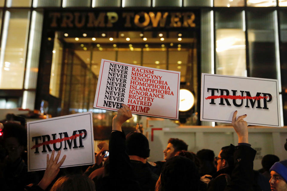 Demonstrators hold signs outside Trump Tower during a protest march against President-elect Donald Trump in Manhattan, New York