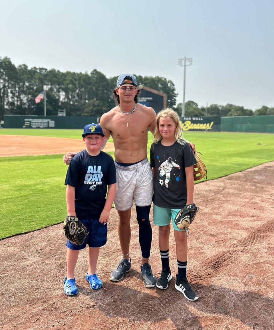 Savannah Bananas outfielder Noah Bridges spends time with fans Reed Williams, left, and his cousin, Asher Berg, after batting practice at Grayson Stadium in Savannah, Georgia, in July 2023.