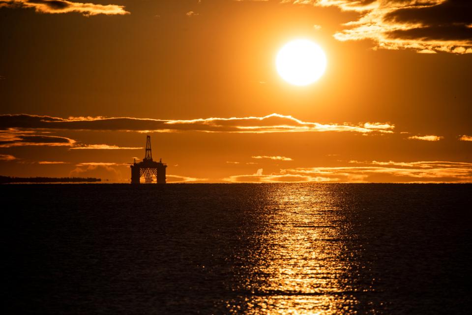 The sun rises behind a redundant oil platform n the Firth of Forth (PA Archive)
