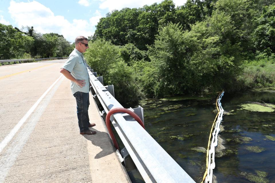 Matthew Gudorf, president and COO of Eco-Maxx, looks at the last boom on the river from a bridge on Center Road over the Tuscarawas River in New Franklin Village. The boom is the 3.9 miles downriver from the site of the spill.