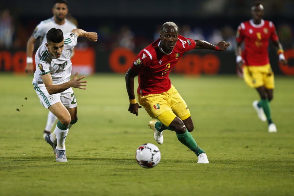 Guinea's Mohamed Yattara and Algeria's Youcef Atal run for the ball during the African Cup of Nations round of 16 soccer match between Guinea and Algeria in 30 June stadium in Cairo, Egypt, Sunday, July 7, 2019. (AP Photo/Ariel Schalit)