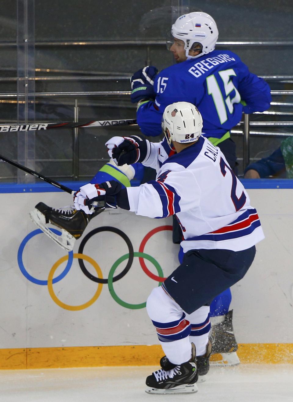 Slovenia's Blaz Gregorc (15) is checked into the boards by Team USA's Ryan Callahan (24) during the first period of their men's preliminary round ice hockey game at the 2014 Sochi Winter Olympics, February 16, 2014. REUTERS/Brian Snyder (RUSSIA - Tags: OLYMPICS SPORT ICE HOCKEY)