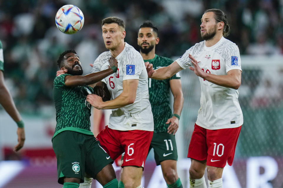 Saudi Arabia's Nawaf Al-Abed, left, and Poland's Krystian Bielik, center, fight for the ball during the World Cup group C soccer match between Poland and Saudi Arabia, at the Education City Stadium in Al Rayyan, Qatar, Saturday, Nov. 26, 2022. (AP Photo/Manu Fernandez)