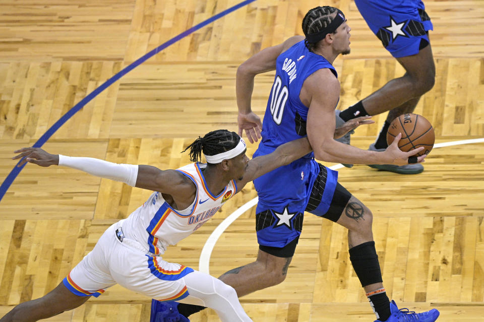 Oklahoma City Thunder guard Shai Gilgeous-Alexander, left, attempts to steal the ball while Orlando Magic forward Aaron Gordon (00) drives to the basket during the second half of an NBA basketball game, Saturday, Jan. 2, 2021, in Orlando, Fla. (AP Photo/Phelan M. Ebenhack)