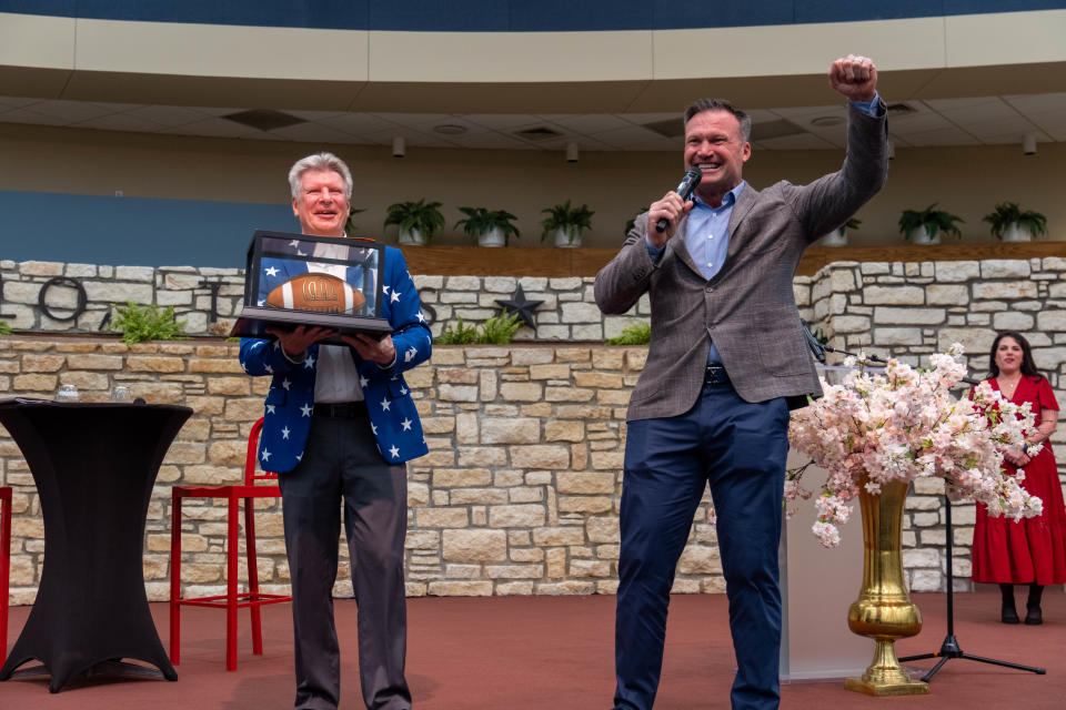 Hall of Famer Zach Thomas celebrates as the bids rise for charity with Lance Lahnert holding the prized autographed football Tuesday at the Heroes and Legends fundraiser event at the Amarillo Civic Center.