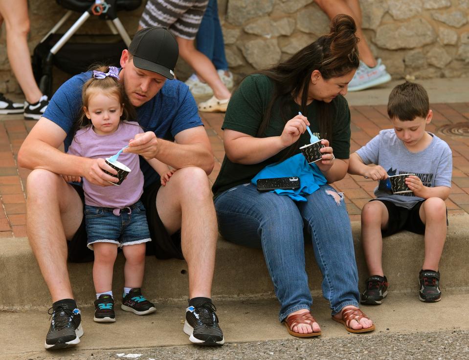 The Mullally  family, Amelia, 2, Billy, Kayla and Grant, 5, eat a treat from The Baked Bear truck while sitting on the curb during Heard on Hurd in downtown Edmond Saturday, May 20, 2023.
