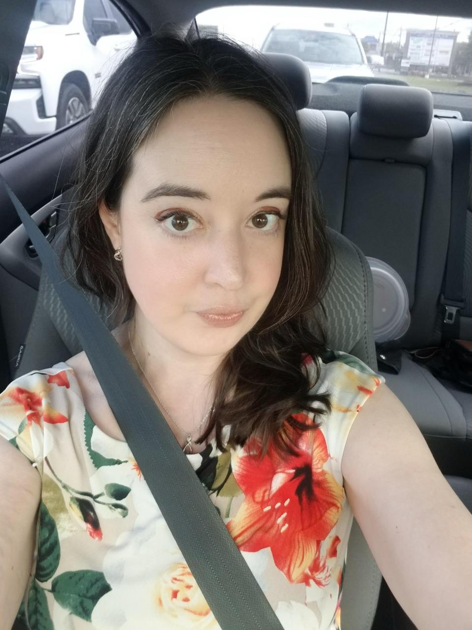 Meghan Bea wearing a floral dress in a car