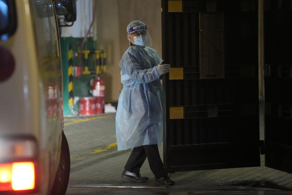 A security guard in protective gear opens the hotel's gate for the arrival of a van carrying overseas quarantine passengers from an airport in Hong Kong on Nov. 30, 2021. The bustling, cosmopolitan business hub of Hong Kong may be losing its shine among foreign companies and expatriates with its stringent anti-pandemic rules requiring up to 21 days of quarantine for new arrivals. (AP Photo/Kin Cheung)