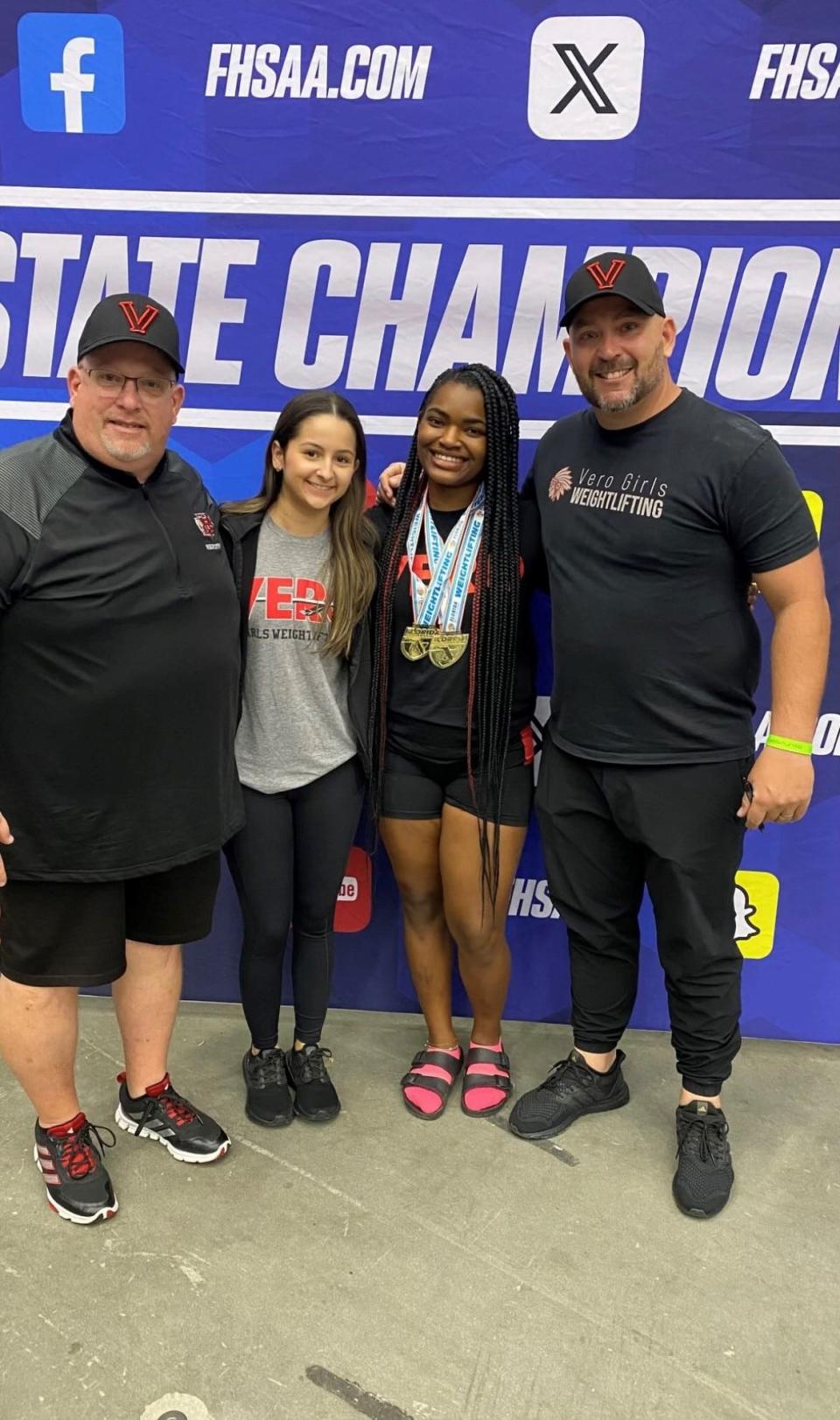 Vero Beach coaches Pete DeLuke (far left), Helaina Thompson (left) and Brian Secrest (far right) poses for pictures with senior Enyjai Tyson after she won a pair of state individual titles at the Class 3A state meet on Friday, Feb. 16, 2024 from the RP Funding Center.