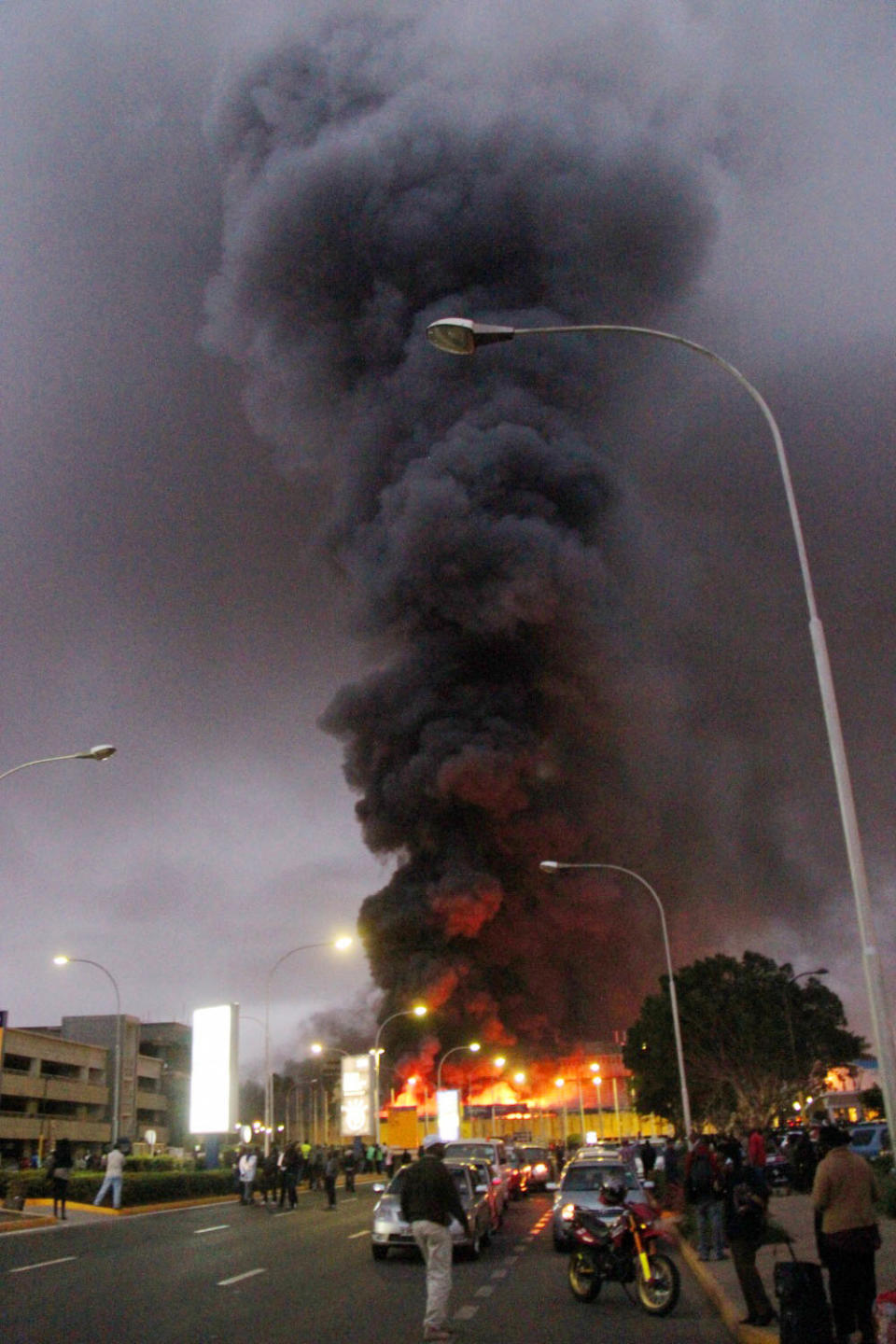 People watch dense black smoke billowing from the Jomo Kenyatta International Airport in Nairobi, Kenya, early Wednesday, Aug. 7, 2013. Firefighters are battling a large blaze raging at Kenya's main international airport. The Kenya Airports Authority said Wednesday that the airport has been closed until further notice so that emergency teams can battle the fire. (AP Photo/Kyodo News) JAPAN OUT, MANDATORY CREDIT