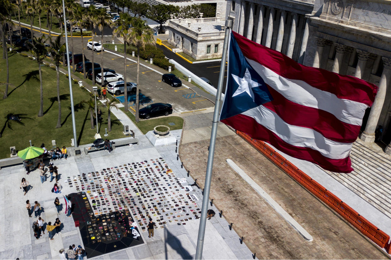 A Puerto Rican flag flies above empty pairs of shoes outside the island's Capitol building. (Photo: Bloomberg via Getty Images)