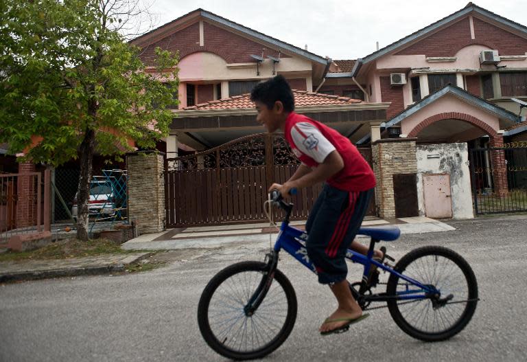 A boy rides his bicycle past the home of missing Malaysia Airlines flight MH370 co-pilot Fariq Abdul Hamid in Shah Alam, on March 16, 2014